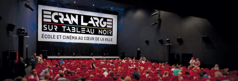 Personnes assises dans une salle de cinéma avec un écran large