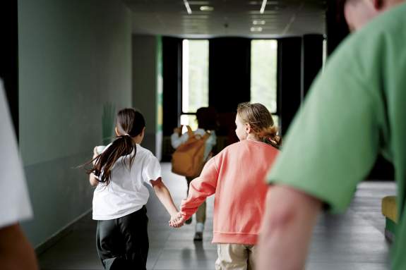 Deux fillettes courent main dans la main dans un couloir