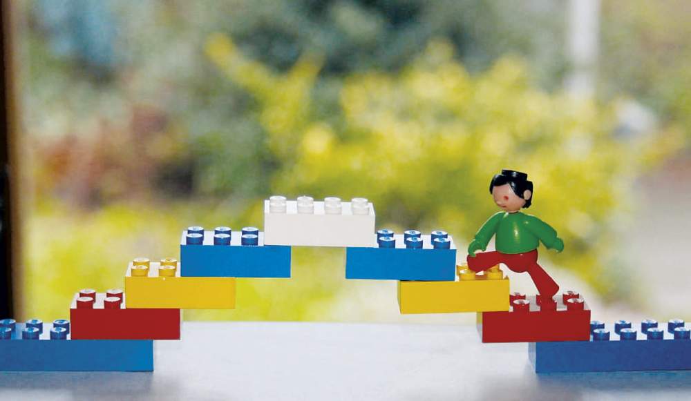Des legos : un bonhomme monte sur un pont coloré